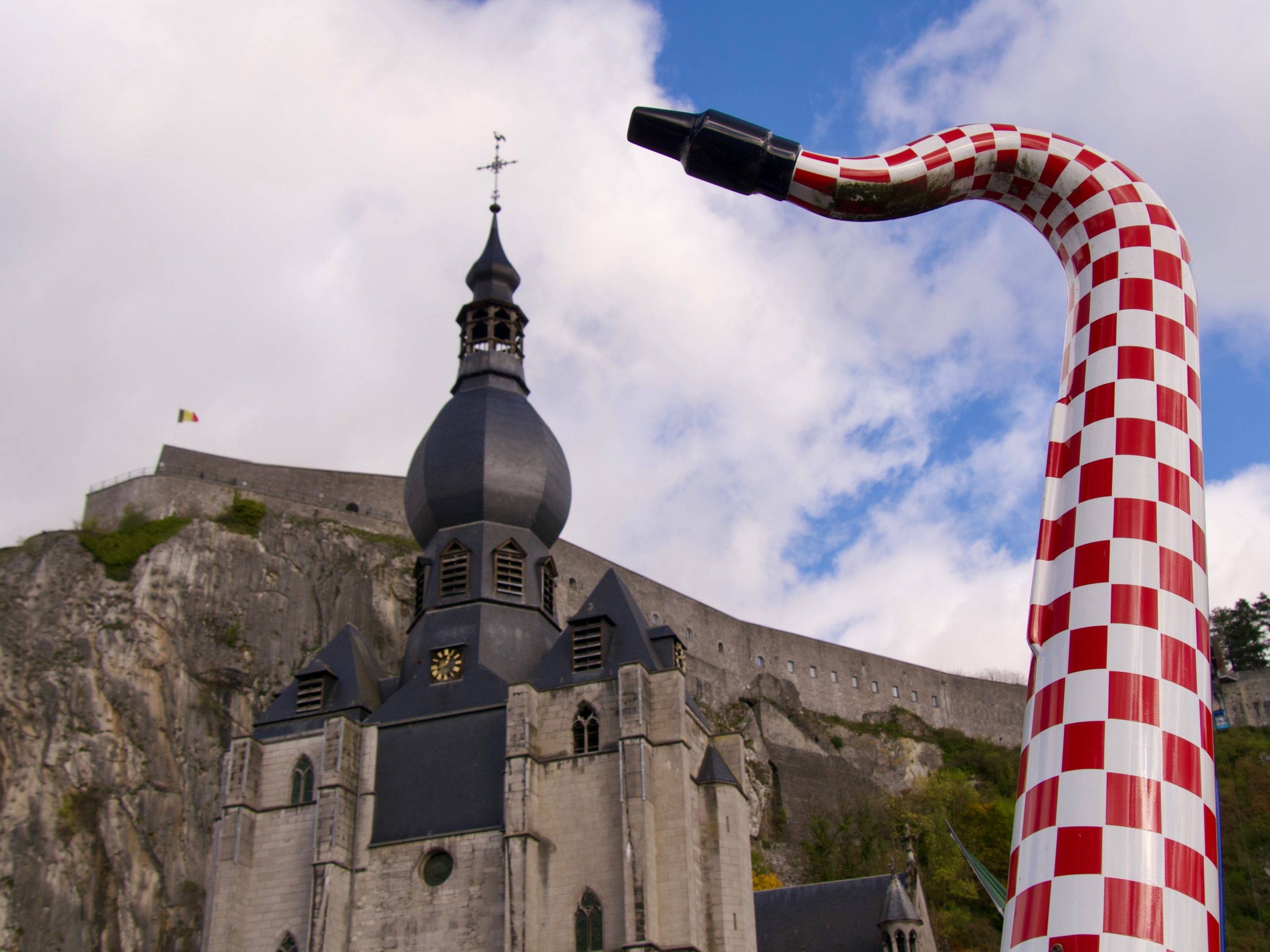 Een saxofoon op de charles de Gaulle brug met zicht op de kerk in Dinant