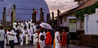 Mensen in witte kleding die naar de stoepa komen in de avond