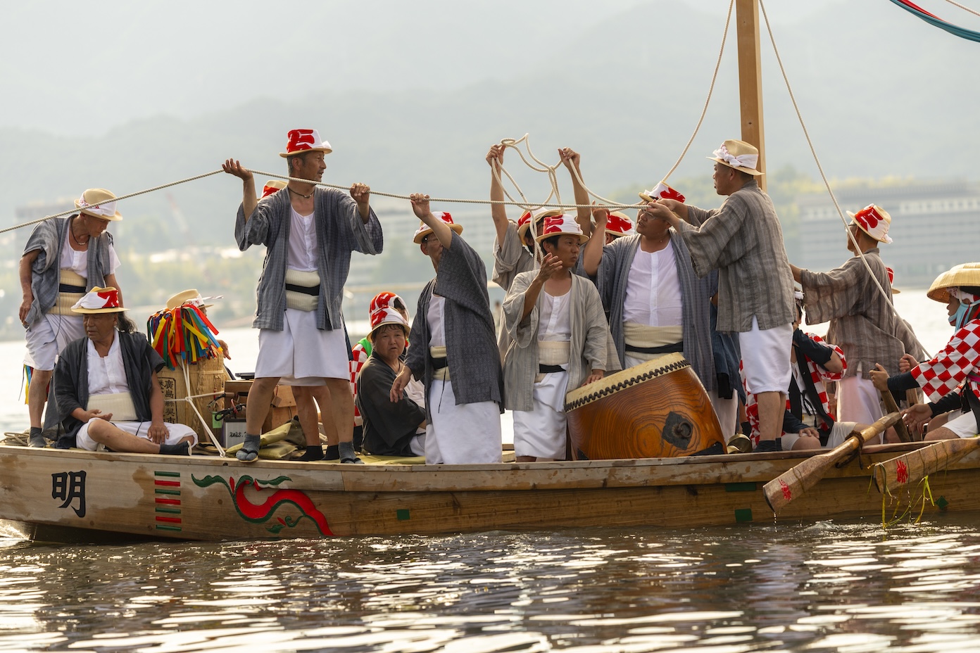 Mannen maken traditionele muziek op de boot tijdens de Kangen-sai ceremonie